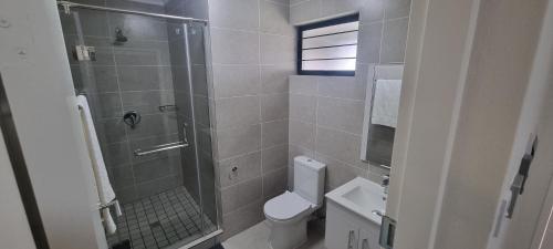 a bathroom with a shower and a toilet and a sink at The Aura in Roodepoort