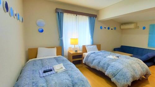 um quarto com 2 camas e um sofá azul em Le Port Awashima em Mitoyo