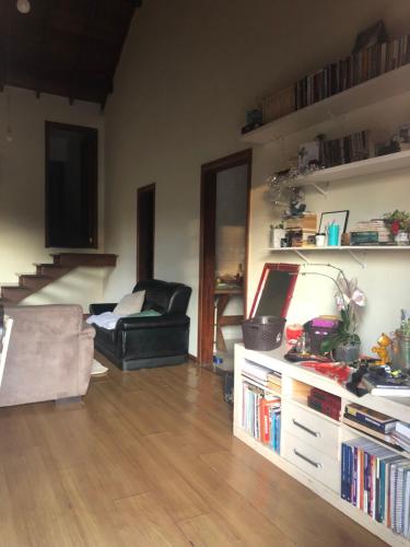 a living room with a couch and a table with books at Quarto aconchegante lago igapó in Londrina