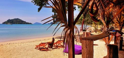einen Strand mit einem Haufen Stühle und dem Meer in der Unterkunft Miss You Beach Resort Koh Mak in Ko Mak