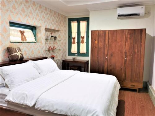 a bedroom with a white bed and a wooden cabinet at Ndalem Kinasih Homestay Syariah in Solo