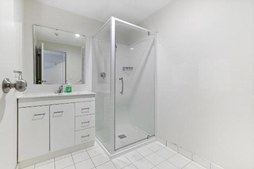 a white bathroom with a shower and a sink at Central Mountain View Paradise in Queenstown