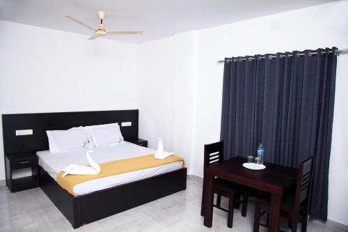 a bedroom with a bed and a table with a chair at Thekkady Travel Rooms in Thekkady
