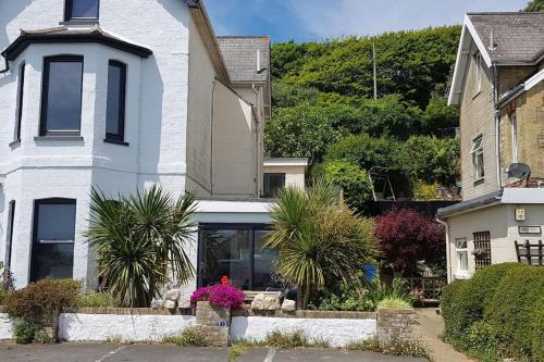 a white house with plants in front of it at Wheelers Bay Apartment in Ventnor