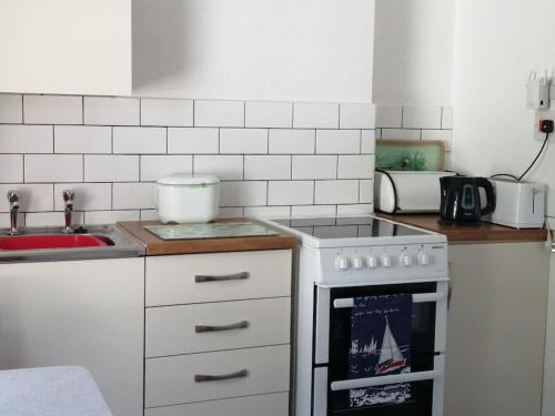 a kitchen with a stove top oven next to a sink at Wheelers Bay Apartment in Ventnor