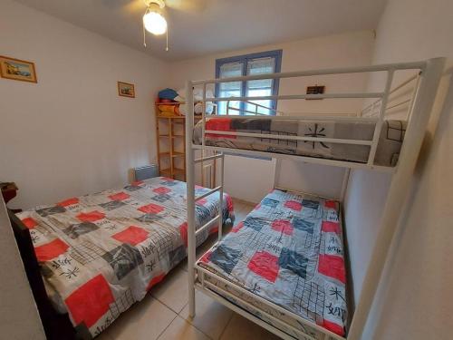 une chambre avec deux lits superposés dans une pièce dans l'établissement Appartement T2 avec Grand Jardin, Terrasse et Parking - 4 Couchages à Marseillan Plage - FR-1-326-740, à Marseillan
