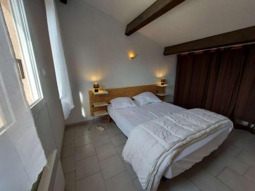 une chambre avec un lit blanc avec une tête de lit en bois dans l'établissement Studio Cabine Mezzanine, 6 Pers, Terrasse Sud, Près Quai, Parking Privé - FR-1-326-755, à Marseillan