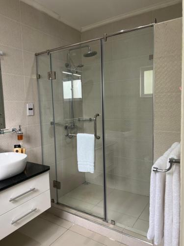 W łazience znajduje się szklana kabina prysznicowa i umywalka. w obiekcie Paul's Residence w Mahé