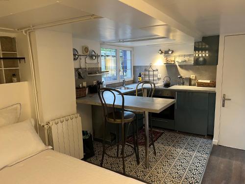 a kitchen with a table and chairs in a room at Petit studio de la Maison du Bonheur - Rez de jardin in Villiers-sur-Marne