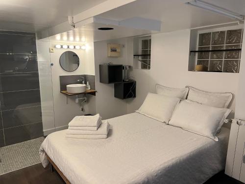 a bedroom with a white bed with towels on it at Petit studio de la Maison du Bonheur - Rez de jardin in Villiers-sur-Marne