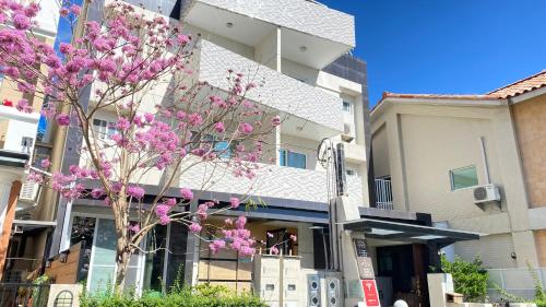 a tree with pink flowers in front of a building at Lohas Taitung B&B in Taitung City