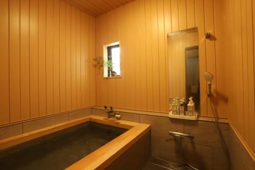 een badkamer met een bad en een raam bij Koguma no ie in Nozawa Onsen