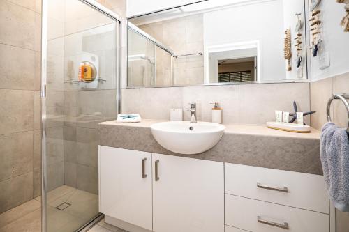 Un baño blanco con lavabo y ducha. en Rainbow Shores Resort Getaway!, en Rainbow Beach