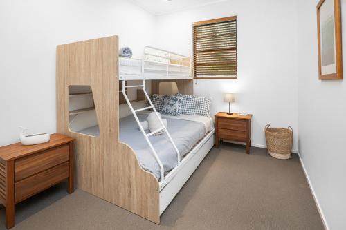 a bedroom with two bunk beds and a desk at Rainbow Shores - 2 Bedroom, modern apartment, sleeps 6, pool, walk to the beach in Rainbow Beach