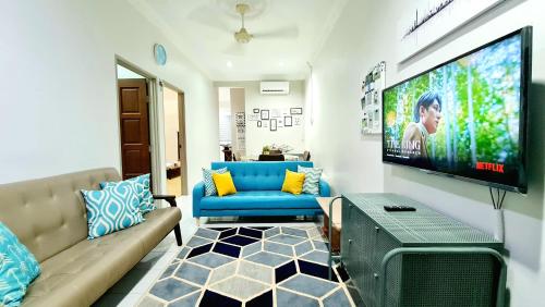 a living room with a blue couch and a flat screen tv at EA Homestay Lembah Bujang Merbok in Bedung