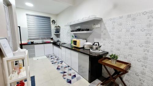 a kitchen with a black counter and white tiles at EA Homestay Lembah Bujang Merbok in Bedung