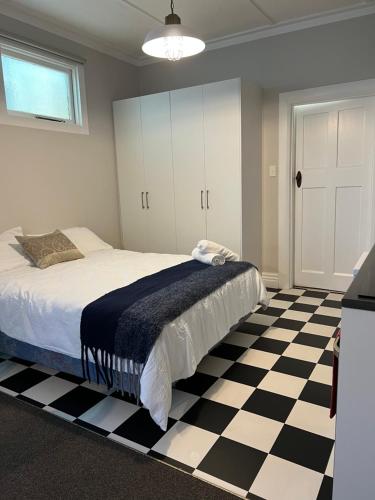 1 dormitorio con 1 cama y suelo blanco y negro a cuadros en Beach Front Studio Napier, en Napier