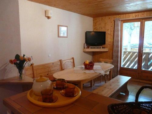 un salon avec une table et une télévision dans l'établissement Chalet Les Eterlous, à Bonneval-sur-Arc