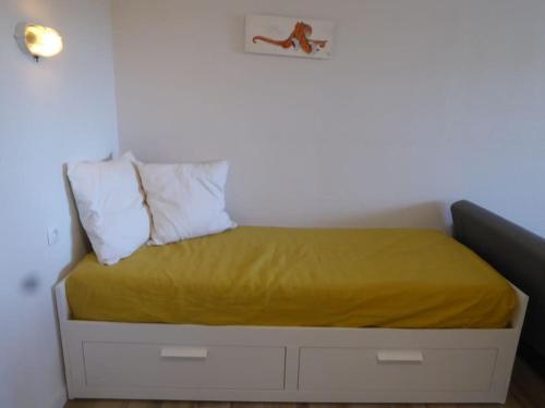 ein Bett mit einer gelben Decke und 2 Kissen in der Unterkunft L'Étoile de Mer - Star Of Sea in Hyères
