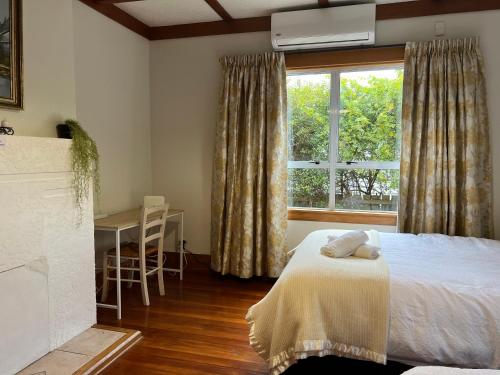 a bedroom with a bed and a window and a table at Rotorua Holiday Villa in Rotorua