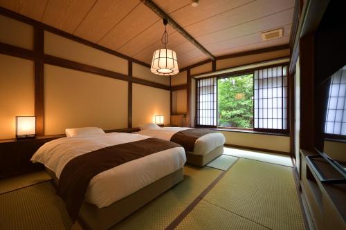a bedroom with two beds and a tv and windows at Syoubun in Minakami