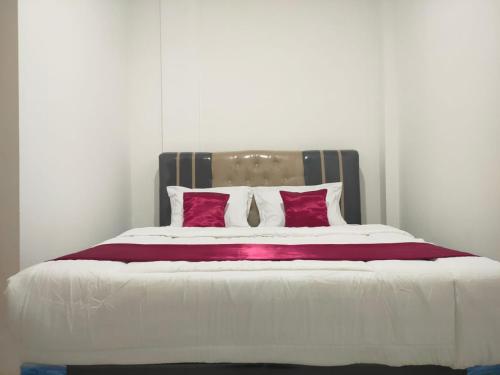 パレンバンにあるHiast Syariah Residenceの大型ベッド(赤と白の枕付)
