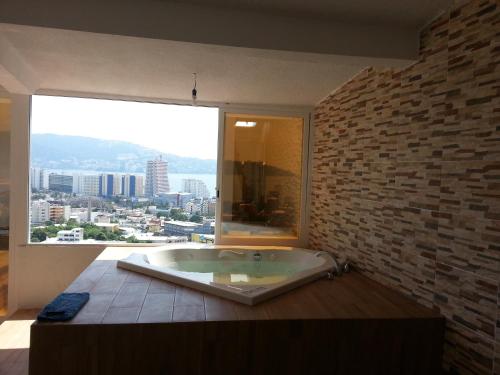 a large bath tub in a room with a large window at Casa Horizonte Azul Acapulco in Acapulco