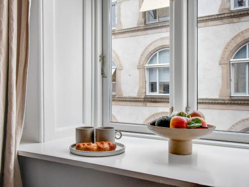 a table with a bowl of fruit and a window at Regent 4- Cute 1-Bdr Apt in Centre of Copenhagen in Copenhagen