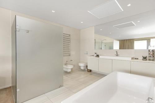 a white bathroom with a tub and a sink at Cape Blue in Cape Town