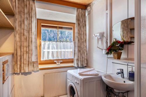 uma casa de banho com uma máquina de lavar roupa e um lavatório em Ferienhaus Wechner em Häselgehr