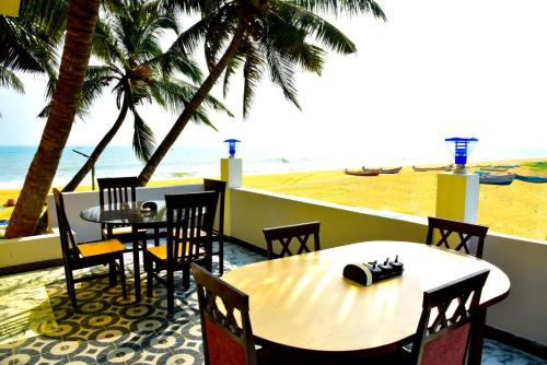 una mesa y sillas con vistas a la playa en Paradise Harmony Beach Resort en Singānallūr