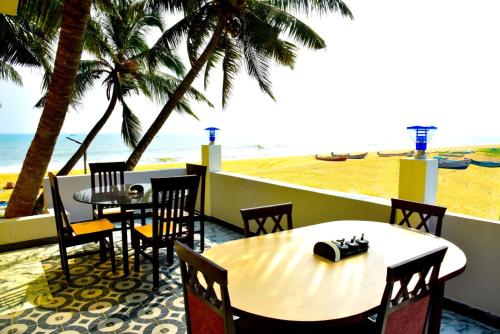 a table and chairs with a view of the beach at Paradise Harmony Beach Resort in Singānallūr