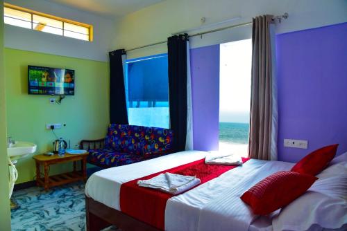 a bedroom with a bed and a couch and a window at Paradise Harmony Beach Resort in Singānallūr