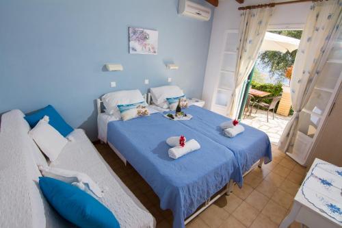 1 dormitorio azul con 2 camas y balcón en Eleni's Apartments, en Barbati