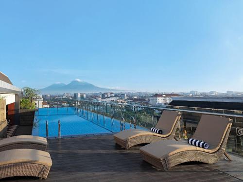 een balkon met 2 stoelen en een zwembad bij Royal Malioboro by ASTON in Yogyakarta