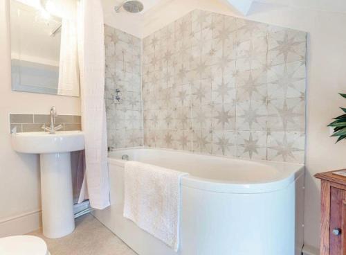 a bathroom with a white tub and a sink at Rosemary Cottage in Bere Alston