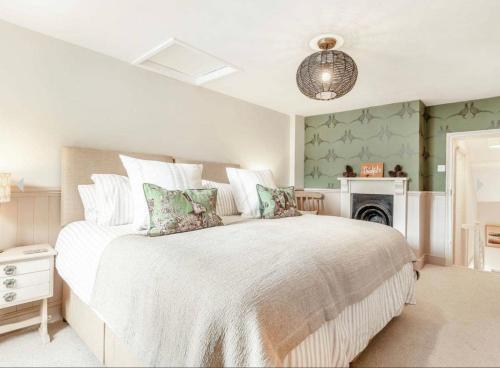 a bedroom with a large white bed and a fireplace at Rosemary Cottage in Bere Alston
