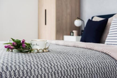 a tray with a cup and flowers on a bed at Sol Marina Resort Wyspa Sobieszewska I - LoftAffair Collection in Wiślinka