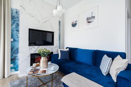 a blue couch in a living room with a table at Sol Marina Resort Wyspa Sobieszewska I - LoftAffair Collection in Wiślinka