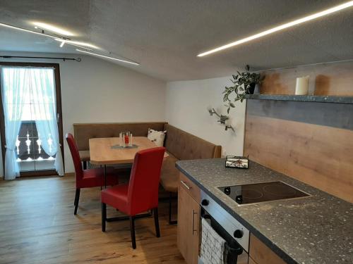 a kitchen and dining room with a table with red chairs at Ferienwohnung Steinlehen in Marktschellenberg