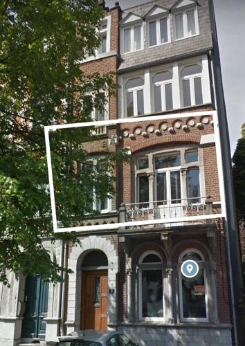 a tall brick building with a balcony on a street at Studio confort Verviers in Verviers