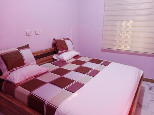 een slaapkamer met een groot bed en een geruite vloer bij Dexxy's Palace Hotel in Koforidua