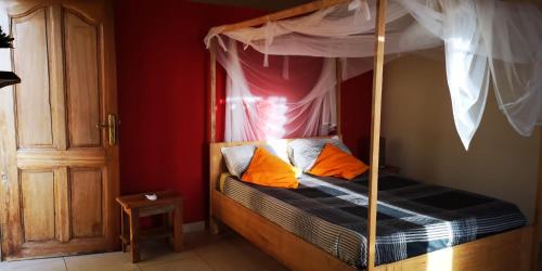 ein Schlafzimmer mit einem Himmelbett und orangefarbenen Kissen in der Unterkunft Chez medzo et patou in Poponguine