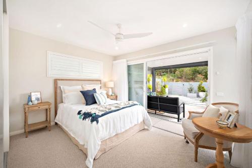 a white bedroom with a bed and a window at 43 Gawul Circuit Corlette in Corlette