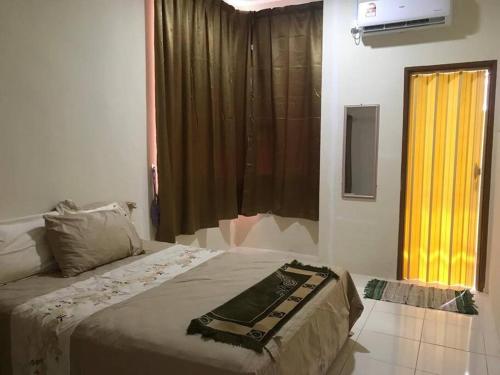 a bedroom with a bed and a large window at HJ Homestay in Kuala Terengganu