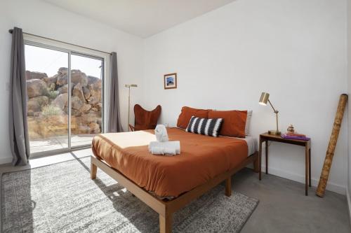 een slaapkamer met een bed en een groot raam bij Rock Box - Modern Adobe Nestled in the Boulders Above Coyote Hol home in Joshua Tree