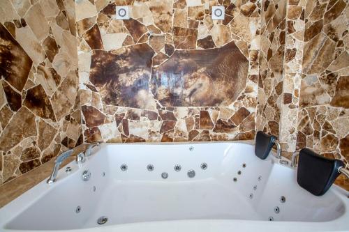 a bath tub in a bathroom with a stone wall at Villa Royal 1 in Kalkan