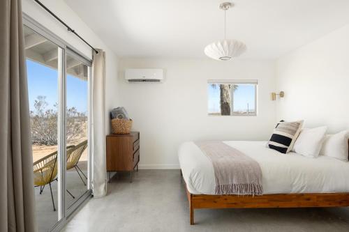 a bedroom with a bed and a balcony at Relax in Style at The Green Jackrabbit - Hot Tub, Record Player home in Sunfair Heights