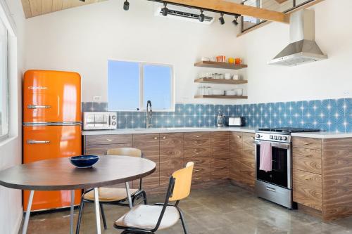 a kitchen with an orange refrigerator and a table at Relax in Style at The Green Jackrabbit - Hot Tub, Record Player home in Sunfair Heights