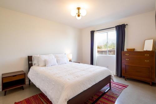 a bedroom with a bed with a dresser and a window at The RockHopper - Hot Tub, Fire Pit & Walk to Downtown JT! home in Joshua Tree